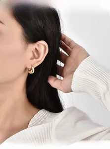 Close-up of chunky gold-plated hoop earrings featuring a polished water drop design
