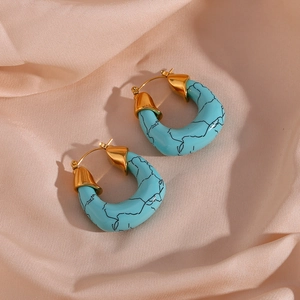 Fashionable horseshoe-shaped gold earrings with turquoise acrylic inlay on champagne satin