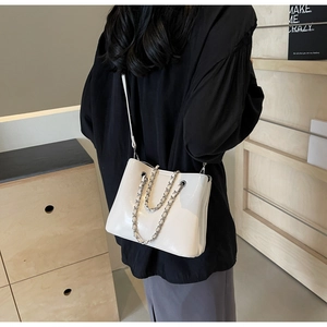Chic white patent leather bucket bag with silver chain handle shown on a model
