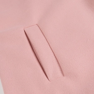 Détail d'une poche de manteau en laine rose montrant les coutures et la texture