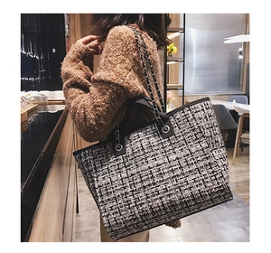 Detail of checkered tweed tote bag with leather and metal chain shoulder strap design