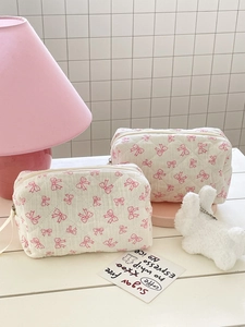 Detail of quilted cotton makeup bags featuring pink bows and a zipper closure