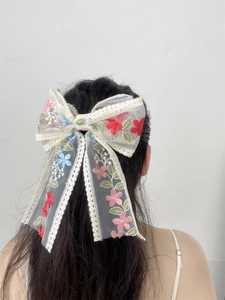 Detailed back view of a large white lace bow hair clip with floral embroidery on hair