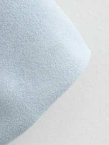 Macro shot of light blue tweed fabric texture on a minimalist short women cardigan