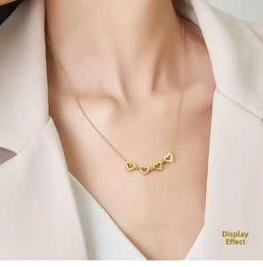 Détail du collier trèfle à cœur doré déplié au cou avec une tenue élégante