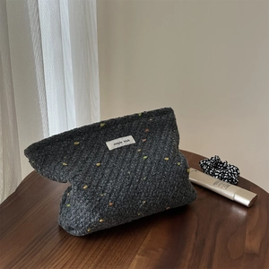 Retro grey woven cosmetic bag with colorful polka dots and simple wish label on wooden table