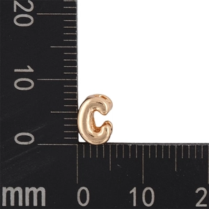 Miniature gold KC letter C charm showing 10mm height measurement on scale ruler
