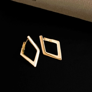 Macro shot of geometric rhombus gold hoop earrings with a polished metallic finish