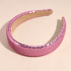 Macro detail of pink sequins on a wide headband with soft beige fabric lining