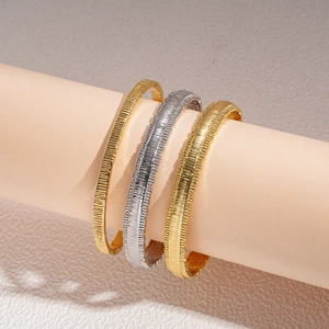 Set of three textured 18k gold and silver plated geometric bangles with a matte finish