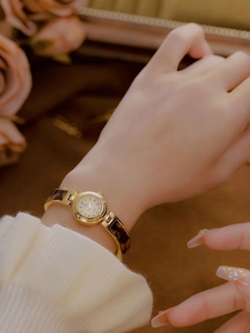 Detail of elegant gold chain watch with amber tortoise shell links on woman's wrist