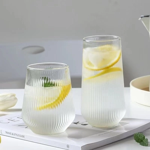 Minimalist vertical ribbed glass cups with lemon slices on a bright, clean white tabletop