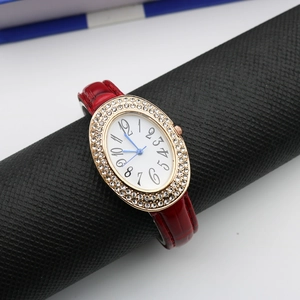 Detail of oval rose gold watch case with double rhinestone bezel and red leather strap