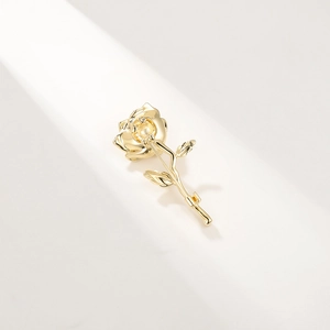 Detailed close-up of a gold-plated rose brooch showing intricate petal and leaf metalwork