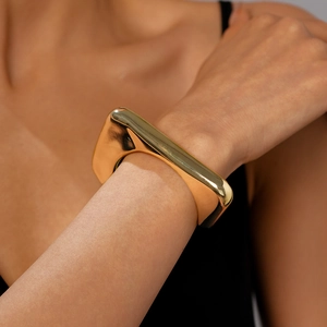 Macro shot of gold geometric triangle cuff bracelet showing polished metallic texture