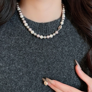 Close-up of elegant pearl necklace with white, silver-gray and lilac beads on a model