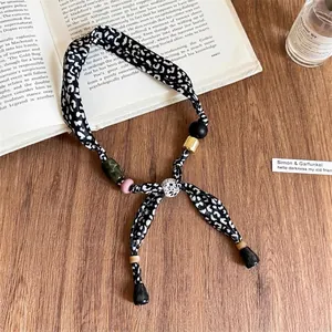 Dettaglio della collana in tessuto leopardato con perline colorate e nappa nera
