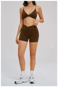 Detail of cross-waist gym shorts and strappy sports bra in dark olive fabric