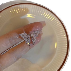 Boucles d'oreilles papillon argentées avec zircons marquise sur un plateau en céramique