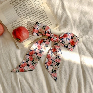 Nœud en soie à fleurs roses posé sur un drap blanc avec des livres et une lumière douce