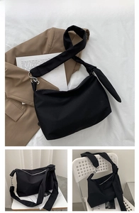 Close-up of black canvas crossbody bag featuring wide knotted straps and zipper closure