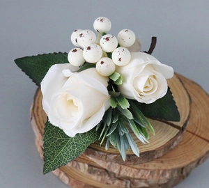 Detail of cream white roses wedding boutonniere on natural wood slice decoration