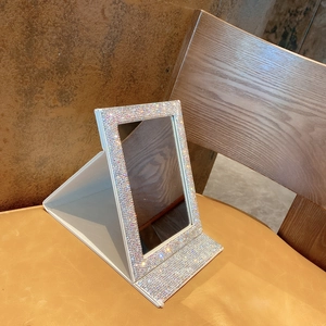 Close-up of foldable makeup mirror with colorful rhinestones and white PU leather texture