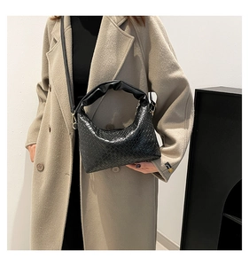 Detailed view of black woven texture and pleated handle on stylish dumpling handbag