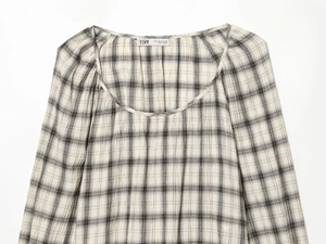 Dettaglio del colletto e della spalla di una camicia elastica a quadretti bianchi e neri