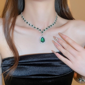 Macro detail of luxury silver necklace with pear-shaped green gemstone and crystal inlay