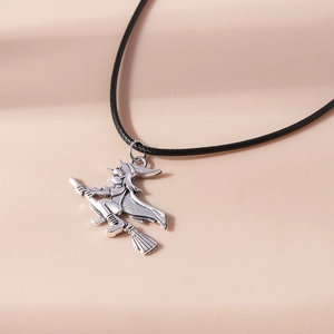 Close-up of vintage silver witch on broomstick pendant with black cord necklace