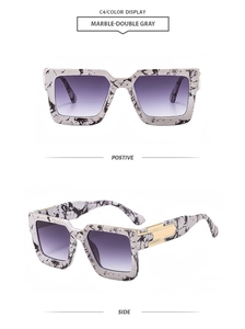 Detail of marble frame sunglasses with purple gradient lenses and gold temple accents