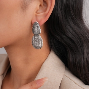 Vue détaillée des boucles d'oreilles ovales argentées avec texture perlée sur un mannequin