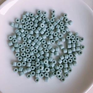 Macro detail of light blue cylindrical acrylic beads on a white ceramic plate