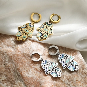 Hamsa-Hand-Ohrringe mit bösem Blick in Gold und Silber auf seidigem Hintergrund