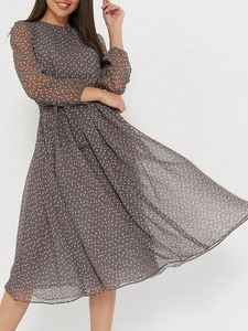 Détail d'une robe maxi grise à pois avec manches longues et ceinture nouée assortie