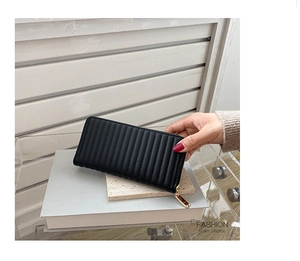 Detailed view of a black long PU leather purse with vertical quilted texture and gold zipper