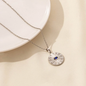 Detail view of silver stainless steel evil eye sunburst pendant with blue inlay on chain