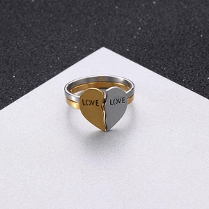 Detailed view of gold and silver interlocking heart rings with LOVE engraving on stainless steel