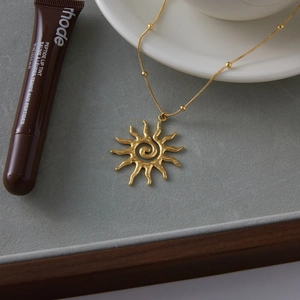 Detail view of 18k gold plated stainless steel sun pendant with a spiral hammered texture