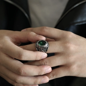 Primer plano de un anillo punk de acero inoxidable con gema verde y símbolo del ojo místico