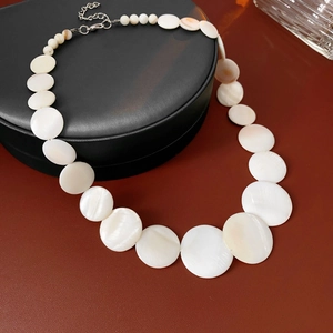 Detailed shot of white shell necklace with geometric pearls in a black gift box