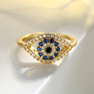 Gold evil eye open ring with blue and white zircons on a textured surface
