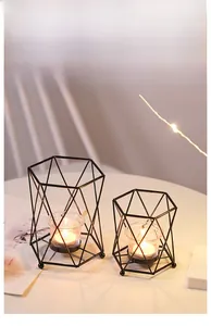 Detail of black geometric wire candle holders with glass inserts on a cozy table