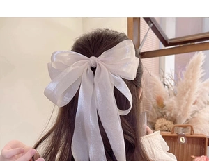 Detail of oversized white organza bow hair clip with elegant long ribbon streamers