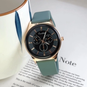 Detail of dark green silicone watch on book page featuring gold chronograph dials