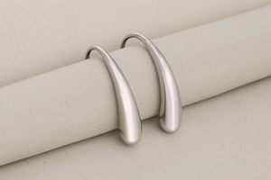 Macro detail of French vintage irregular teardrop earrings in brushed silver finish