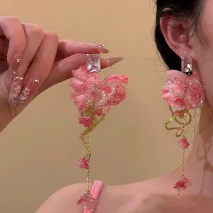 Vue détaillée de boucles d'oreilles à pompons floraux avec pétales de soie roses