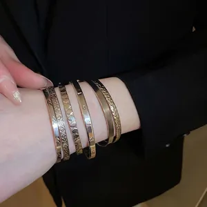 Luxurious gold metal bangle set featuring love motifs and embossed patterns on a model