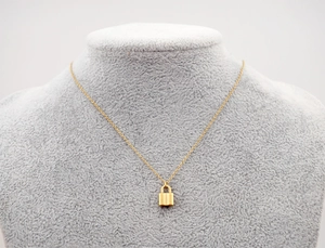 Gros plan détaillé d'un collier pendentif cadenas cœur doré sur un buste en velours gris